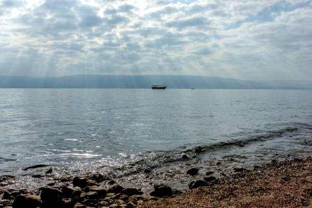 os raios de deus sobre o mar da galiléia com barcos em silhueta. - lake tiberius - fotografias e filmes do acervo