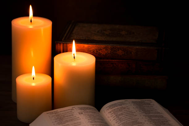 istock Three Candles Lit in a Dark Room with a Bible 1332205250