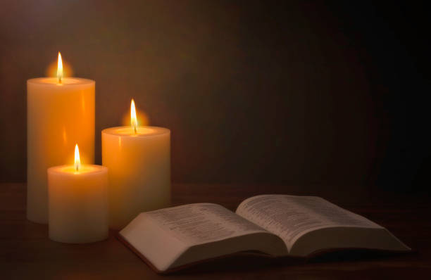 istock Three Candles Lit in a Dark Room with a Bible 1332205251