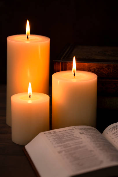 istock Three Candles Lit in a Dark Room with a Bible 1332205283