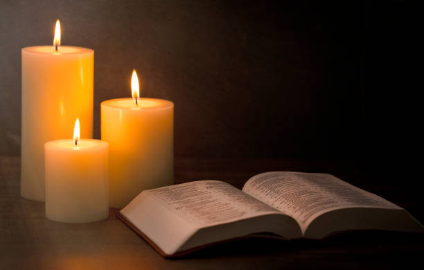 istock Three Candles Lit in a Dark Room with a Bible 1332205292