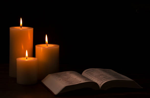 Three Candles Lit in a Dark Room with a Bible
