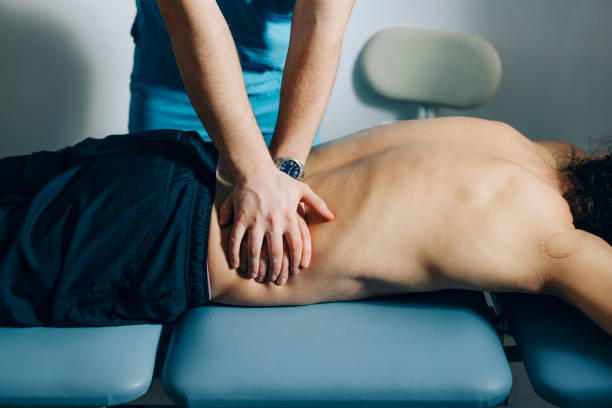 физиотерапия: мануальный терапевт делает массаж спины пациентам - massaging sport men professional sport стоковые фото и изображения