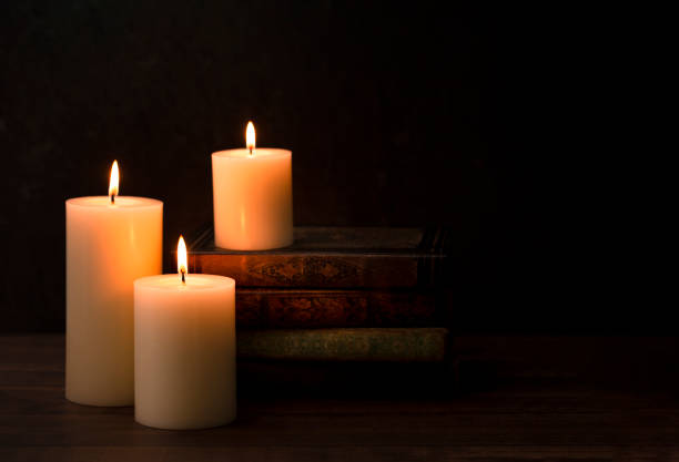 Lighting candle near old books. Vintage still life with medieval books