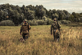 istock Hunters going through rural field towards forest during hunting season 1332205843