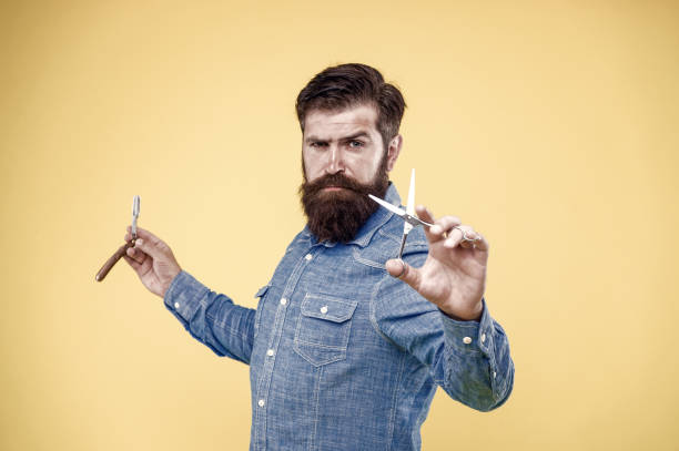 istock Retro and old-fashioned. Bearded man hold retro razor and scissors. Professional barber with retro tools at work. Retro barbershop specialized in classic cuts, vintage filter 1332206592