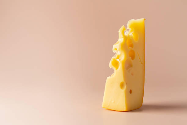 istock A piece of Maasdam cheese on a pastel light pink background. 1332208027