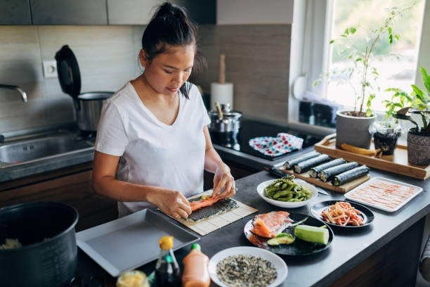 istock Thai woman using bamboo mat to roll up the traditional sushi 1332208206