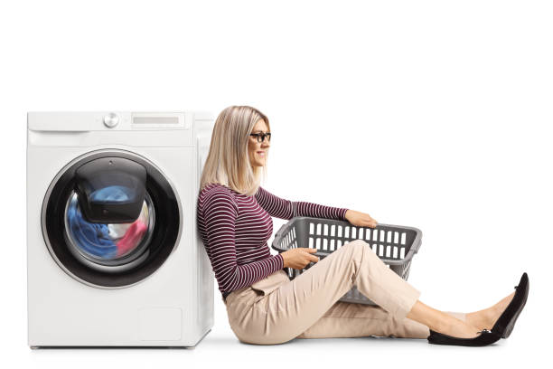 istock Woman with a laundry basket sitting and leaning on a washing machine 1332210053