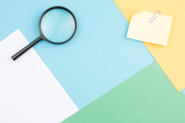 istock Colored paper background with magnifying glass 1332212784