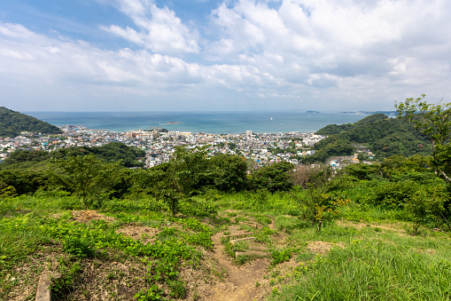 Mid adult female friends wearing huarache sandals or barefoot hiking on mountains in Miura Peninsula, to enjoy walking in nature and viewing the scenery of mountains and pacific ocean.