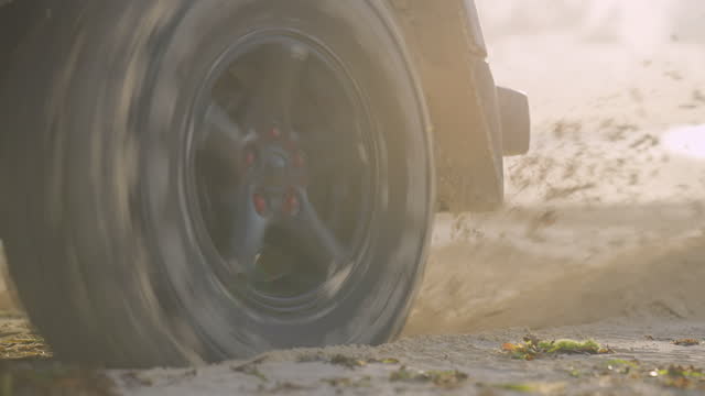 Water and sand splashing from SUV wheels. Beach trip, close up