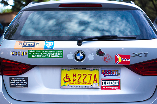 Santa Fe, NM: A man walks past a truck covered with Southwest USA bumper stickers.