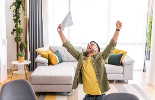 istock Happy young man holding paperwork and celebrating. 1332229876