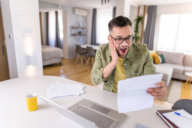 istock Ecstatic young man reading from a document with great news and at home. 1332229904