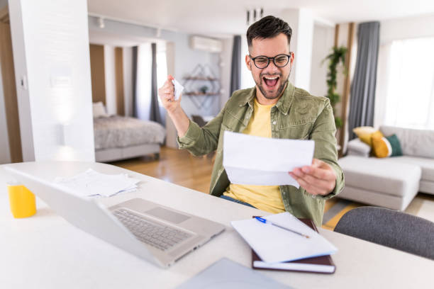 istock Happy young man going through paperwork and celebrating. 1332229921