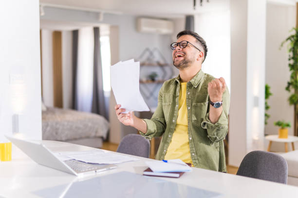 istock Happy young man going through paperwork and celebrating. 1332229950