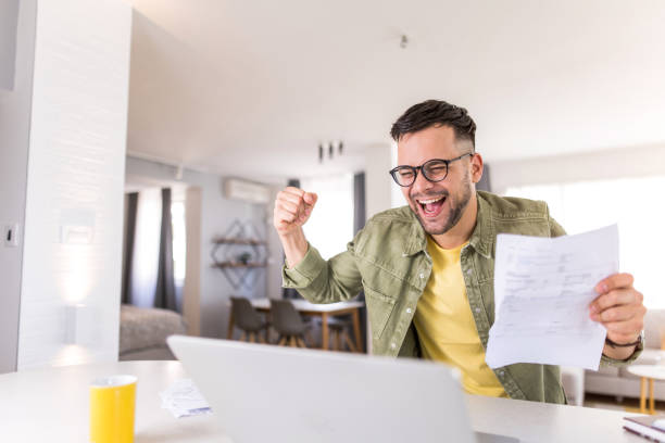 istock Happy young man going through paperwork and celebrating. 1332229955