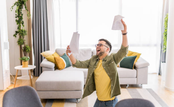 istock Happy young man holding paperwork and celebrating. 1332229986