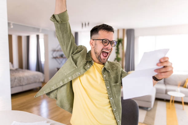 istock Happy young man holding paperwork and celebrating. 1332229999