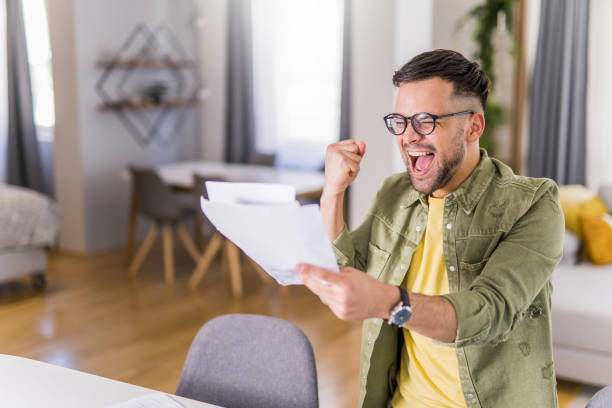 istock Happy young man holding paperwork and celebrating. 1332230003