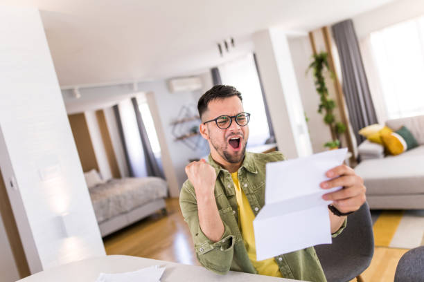 istock Happy young man holding paperwork and celebrating. 1332230012