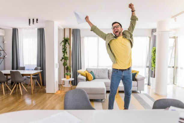 Happy young man holding paperwork and celebrating.