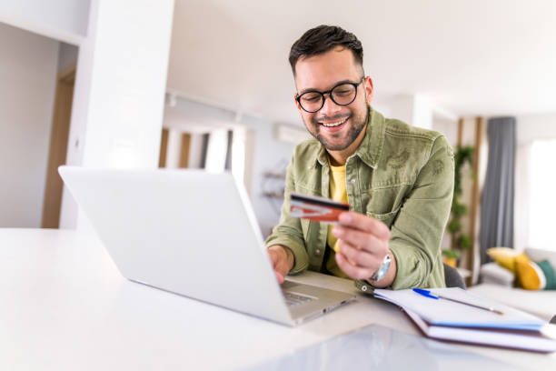 istock Young man using credit card to pay online. 1332230532