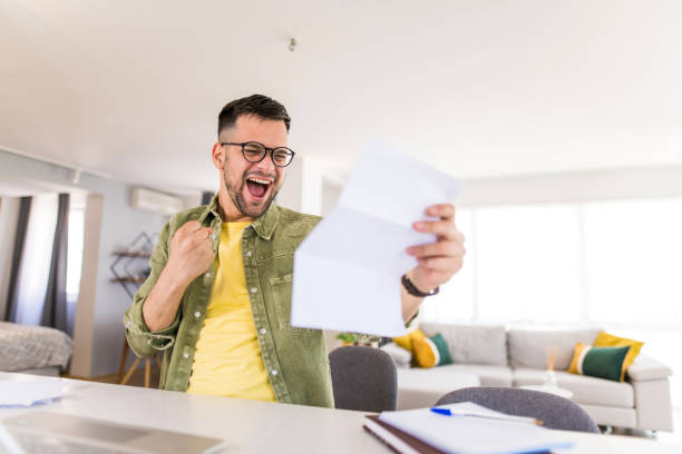 istock Happy young man holding paperwork and celebrating. 1332230610