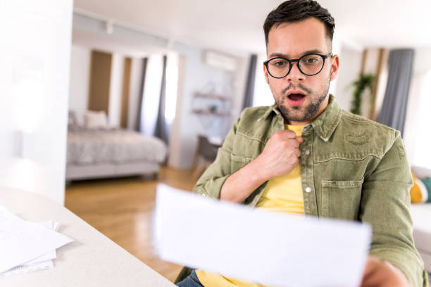 istock Shocked young man going through paperwork at home. 1332230687