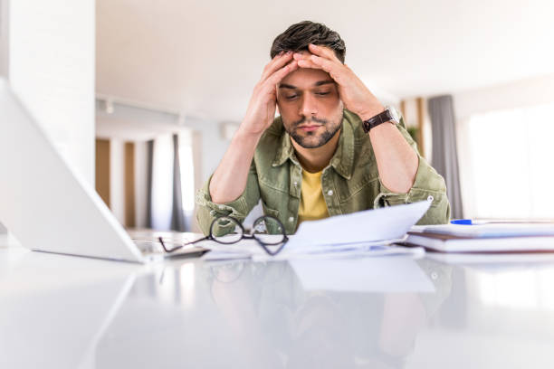 istock Overworked young man going through paperwork at home. 1332231348