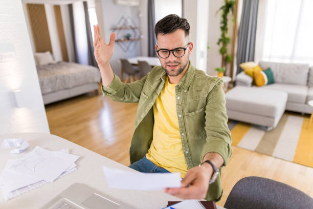 istock Frustrated young man reading from a document at home. 1332231387