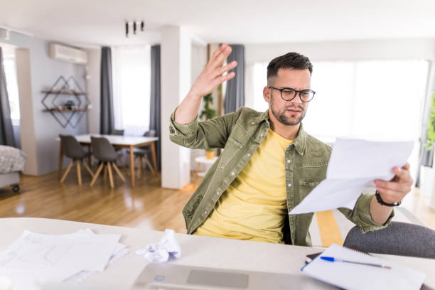 istock Frustrated young man going through paperwork at home. 1332231393