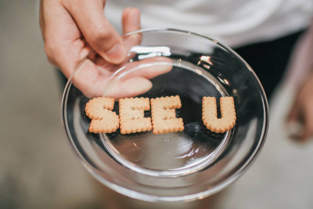 inscripción hecha de galletas "see you" placa con alfabeto galletas sobre mesa de madera con fondo más azul. foto de la vista superior. - eating child cracker asia fotografías e imágenes de stock