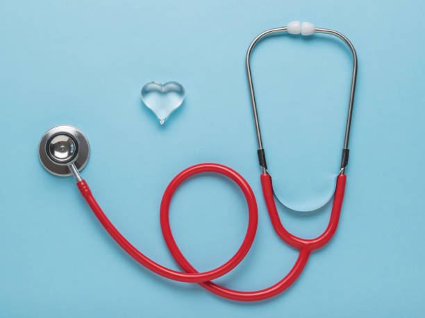 istock A beautiful glass heart and a red stethoscope on a blue background. Flat lay. 1332241229
