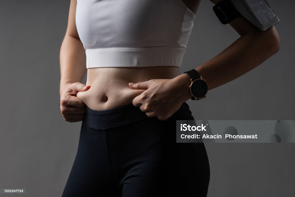 Closeup body of woman in sportswear healthy exercise with fat on belly problem. Closeup body of woman in sportswear healthy exercise with fat on belly problem. Cellulite on fat belly. Concept lose weight of person. Reduction Stock Photo