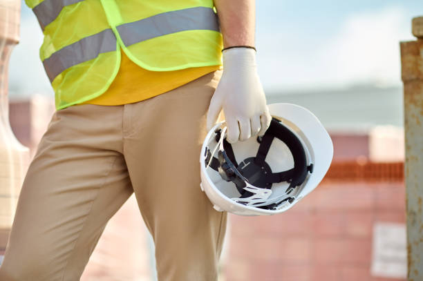 istock Builder in a reflective waistcoat carrying his hardhat 1332251181