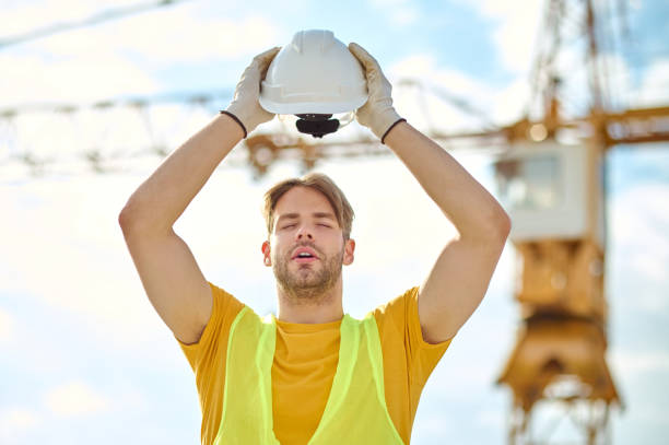 istock Exhausted worker with his eyes closed holding his hardhat overhead 1332251182