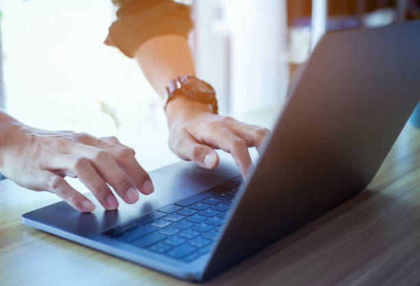 istock closeup man hand using laptop on desk office place, man is working remotely at home 1332254487