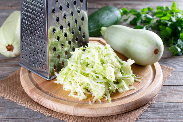 istock Grated zucchini with grater on board on table. Healthy vegetarian ingredient 1332259716