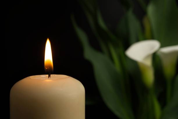 istock Candle burning flame in the darkness and arum lilies 1332259829