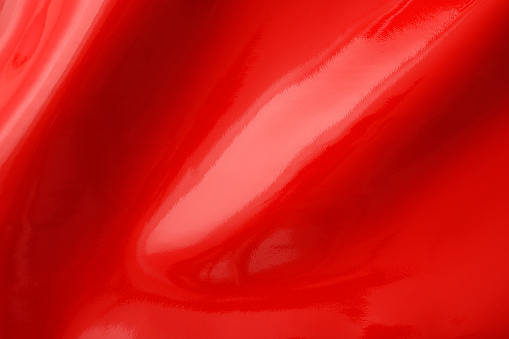 Close-up of red shiny vinyl wave texture background.