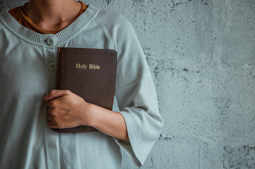 Woman holding a Bible on white background.