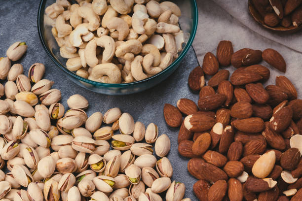 istock mixed nuts in ceramic bowls, wooden spoon. Almonds, walnuts, cashew nuts, pistachio nuts 1332268912