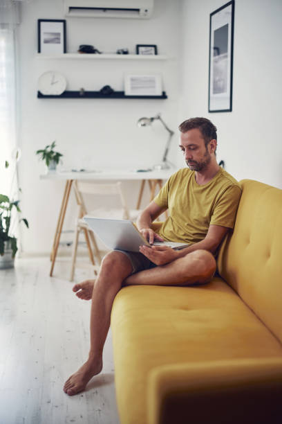 istock Man working on a laptop from the living room. Work from home concept. 1332269676