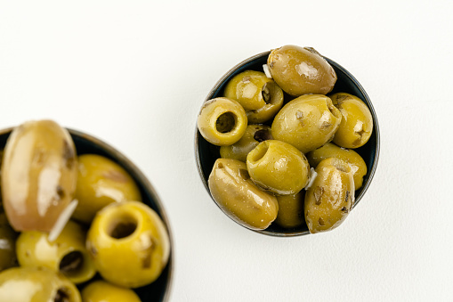 Close-up of olives in bowls on wooden table with copy space.\nShot with a 35-mm full-frame 61MP Sony A7R IV with FE 90mm F2.8 Macro-lens.