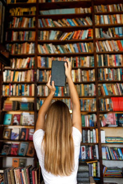 istock Young female student study in the library holding book , education concept 1332273040