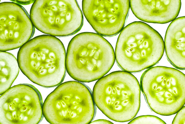 istock Cucumbers in section on a white background. Pieces of cucumber are illuminated by light. Texture of sliced cucumber slices. 1332274331