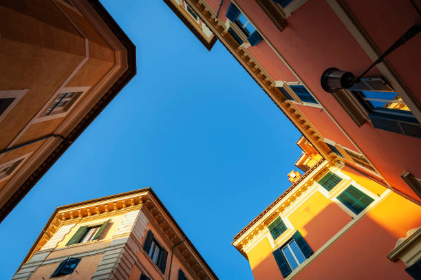 Low angle shot of old buildings in pastel colours and blue sky on Pastini street (Via dei Pastini) in historic centre of Rome, Italy Low angle shot of old buildings in pastel colours and blue sky on Pastini street (Via dei Pastini) in historic centre of Rome, Italy alley photos stock pictures, royalty-free photos & images