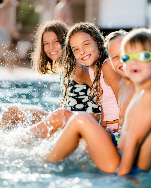istock Playful kids having fun while splashing water in the swimming pool 1332275321